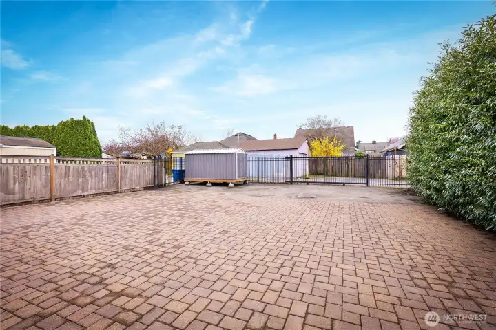 Full stone-paver driveway and rear parking, plus storage shed and gated fencing with rolling alley gate.