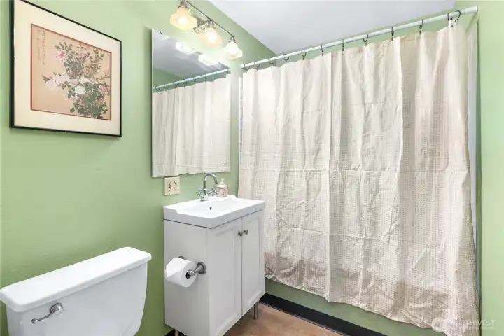 Updated first-floor full bathroom featuring a modern vanity and toilet, wood flooring, and a vinyl window for natural light.