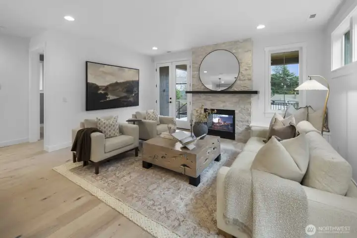 This angle captures the warmth of the great room, where soft natural light, layered design, and a central fireplace create an inviting everyday retreat.