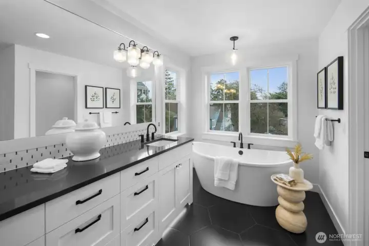 Another view of the primary bath highlights the freestanding soaking tub, expansive vanity, and natural light that softens the entire space.