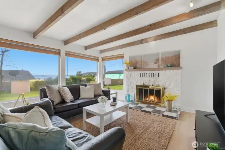 Charming, cozy fireplace home with big picture windows, vaulted beamed ceiling and wonderful wood LVT flooring for warmth and easy care.