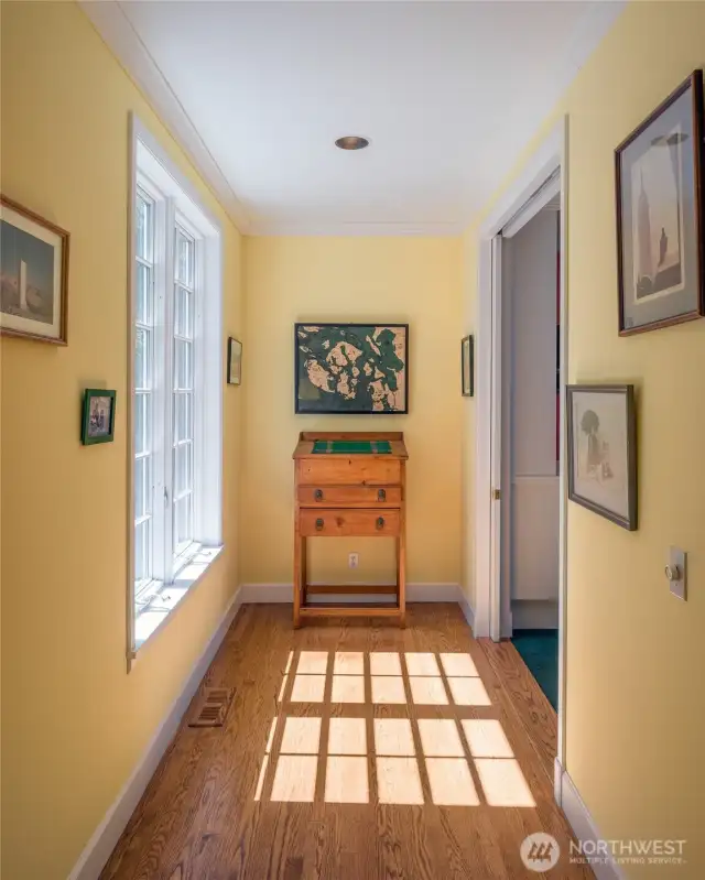 Short part of the sunny gallery hall with door to den on the right.