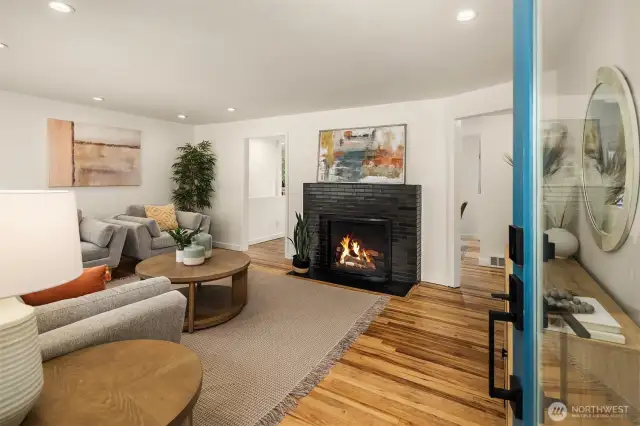 Bright living room with hardwood floors and fireplace (fire added for looks, buyer to verify functionality).