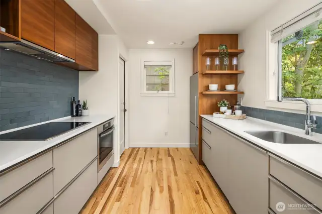 Kitchen with sleek cabinets, open shelving + picture view windows.