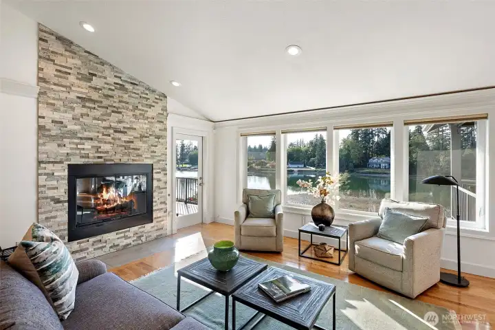 Sun soaked Great Room with hardwood floors and gas fireplace with stone surround