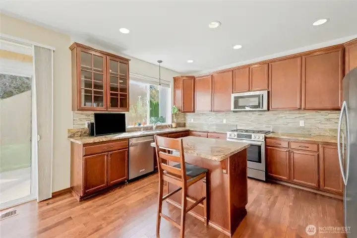The open kitchen is the heart of the home with center island, recessed lighting, and large window above the sink.