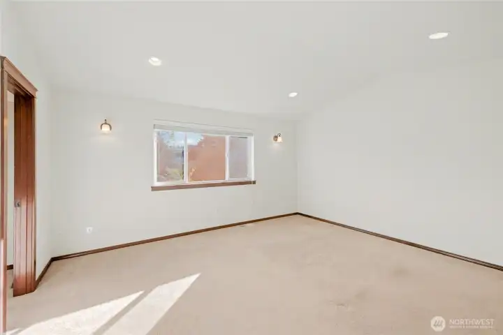 The spacious primary bedroom offers plenty of room to relax, with vaulted ceilings, recessed lighting and large window that floods the space with natural light.