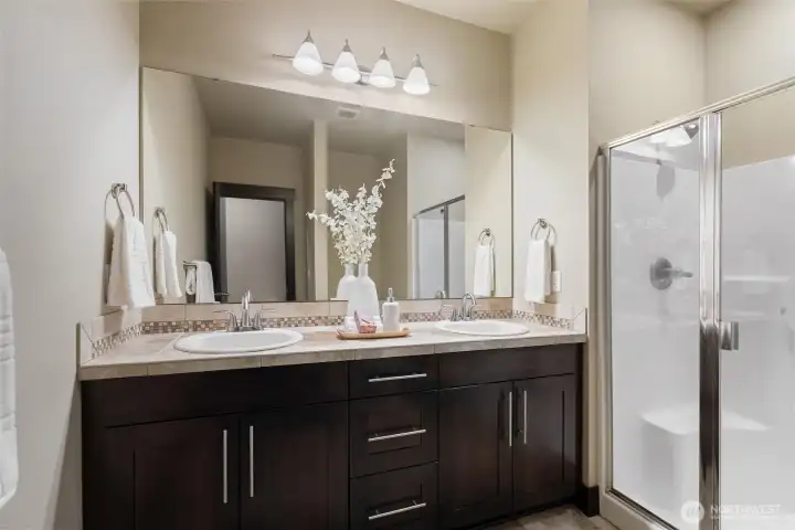 Primary bathroom featuring double vanity and glass-enclosed shower.