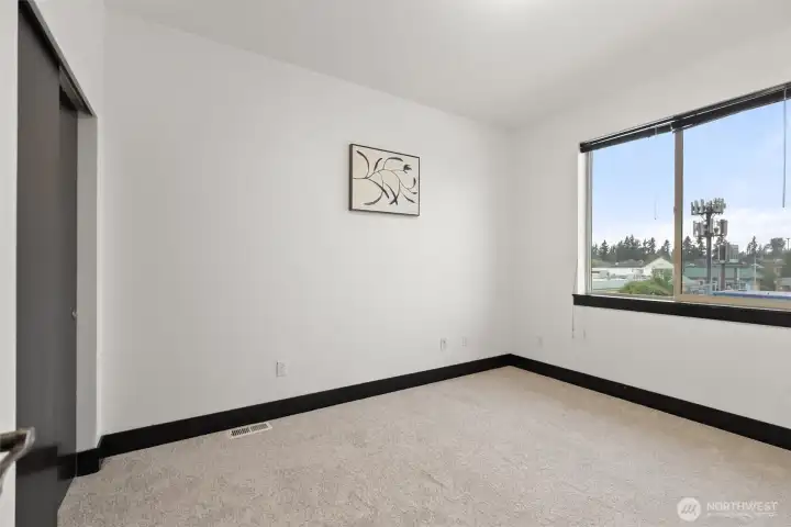 Secondary bedroom with large window and bright, neutral finishes.