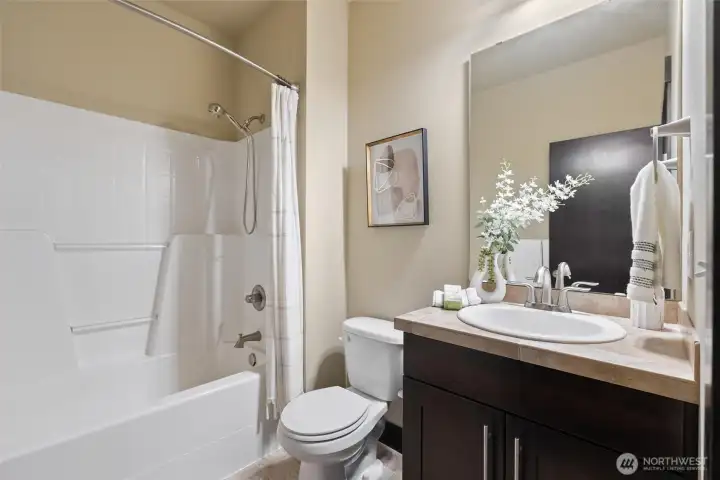 Full guest bathroom with tub/shower combination and modern vanity.