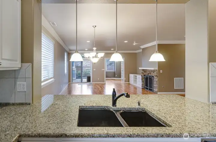 Detailed description of the image: This photo captures the expansive openness of the home, showcasing a welcoming perspective from the kitchen. The shot provides a clear view that extends seamlessly from the kitchen into both the dining and living room areas, highlighting the interconnectedness and flow of the interior spaces.