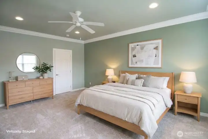 Spacious primary suite has room for the largest of bedroom sets. Crown molding and ceiling fan.