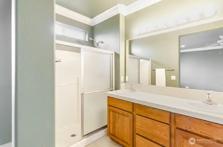 Primary bath with extended shower, double sinks, and private toilet area.
