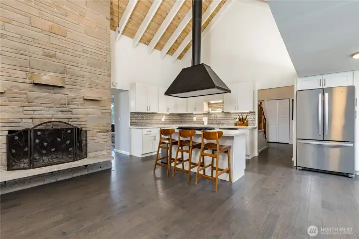 The floor-to-ceiling fireplace and professional-grade kitchen create a breathtaking central hub for the home