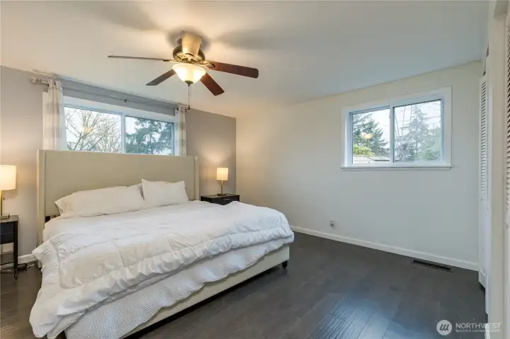 Primary bedroom on the main level includes dual closets and rich engineered hardwood flooring