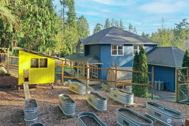 Fenced-in garden area with raised beds and a chicken coop!