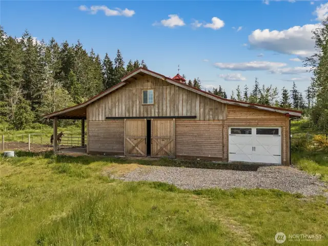 Functional and well-designed barn with drive-through garage, 4 stalls, breezeway, and convenient tack room for all your horse care needs.