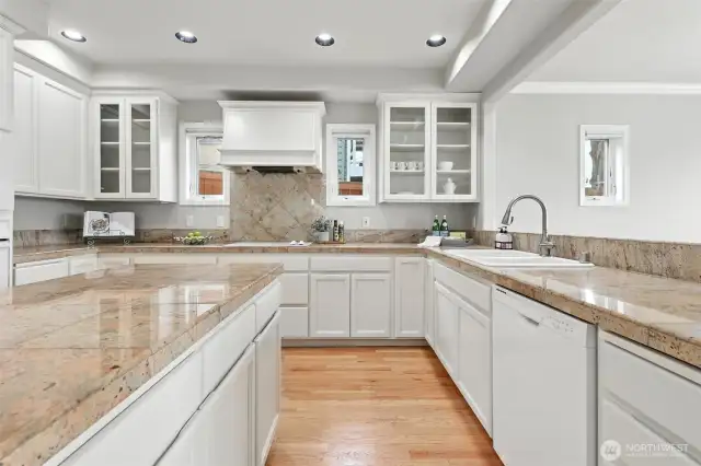 The timeless kitchen is a cook's dream with granite counters, large island, white cabinets and all white appliances.