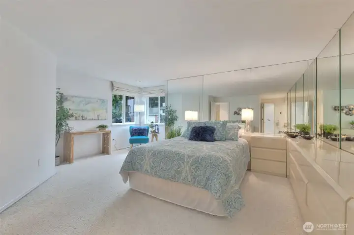 Another view of the primary bedroom. There is a slight view of the water from the window. Dressers units can stay.