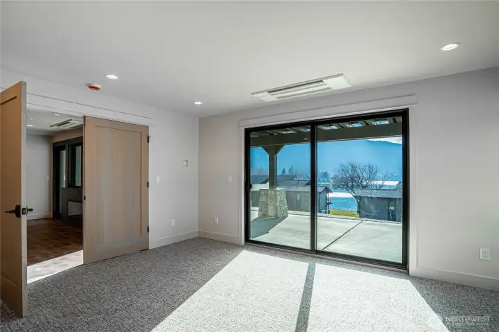 Primary bedroom with large glass sliding door opens to the lakefront patio.