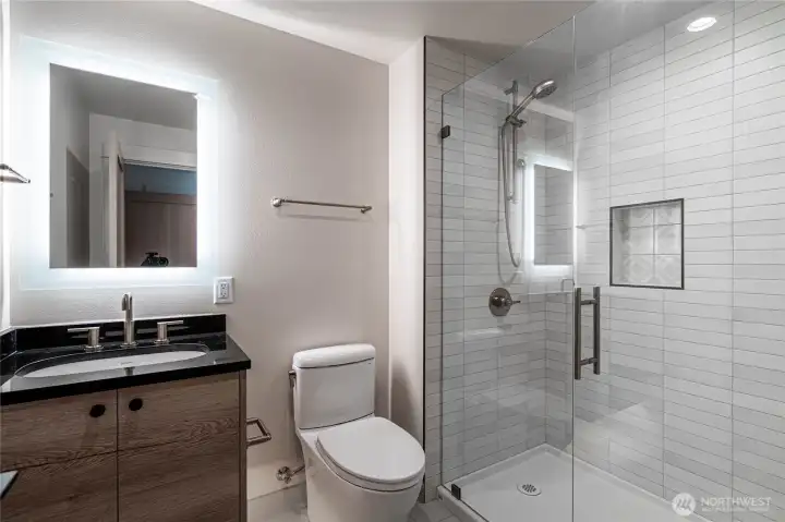 The second bedroom includes its own en suite bathroom with oversized shower and halo mirror vanity.