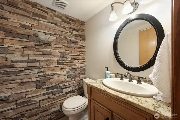 Half bath is conveniently adjacent to family room and nicely accented with this rock wall and marble countertop.