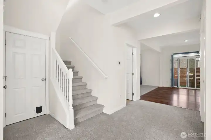 View from dining / living room into kitchen and family room, utility room on right before wood floor.  All new carpet throughout - March 2026.  All new paint throughout (ceilings & walls) - March 2026.