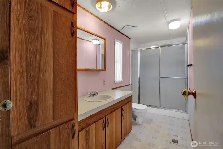 Primary bathroom with a full shower and lots of cupboards for storage and towels.