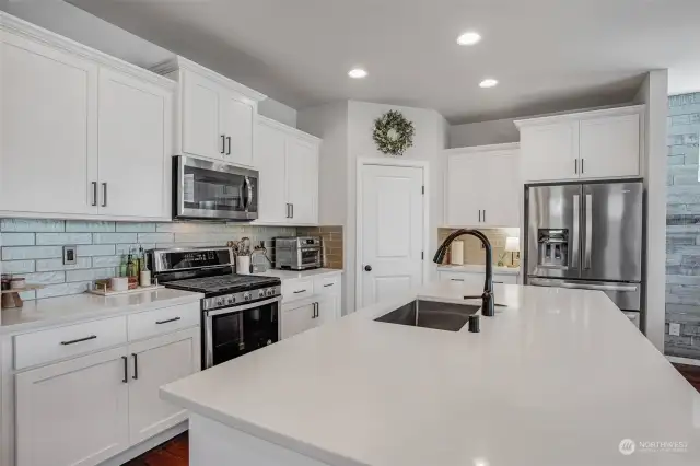 Gorgeous quartz countertops are completed by a lovely backsplash and stainless-steel appliances.