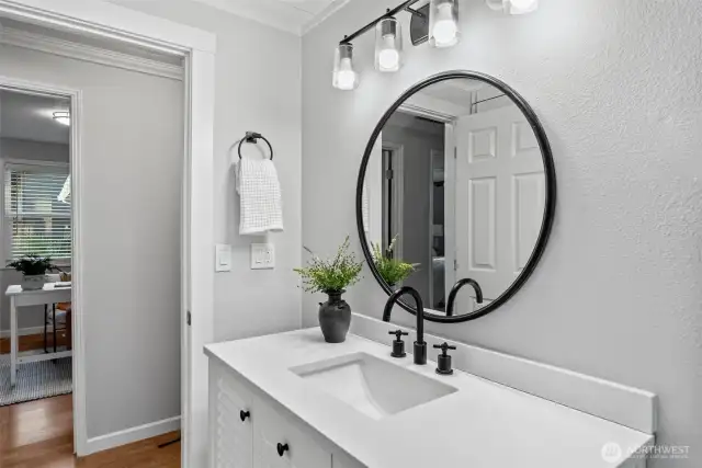 Light and bright, this bathroom features sleek white tiles, stylish black fixtures, a durable vinyl plank floor, skylights, a shiplap ceiling, and a large frosted window ensuring privacy without sacrificing natural light.