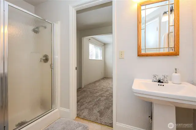 This bathroom features a linen closet, walk-in shower and pedestal sink.