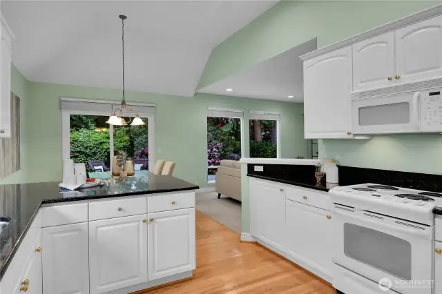Light, bright kitchen with paneled white cabinets, shiny-brass hardware. Grocery pantry with paneled Quaker door, coated ventilated wire shelving. Oak-hardwood floor in kitchen extends into the breakfast area. Maytag® bottom freezer refrigerator. Upgraded countertops with full bullnose finished edges. GE® range-oven with GE® Spacemaker XL microwave oven above. Kenmore® dishwasher. Undermounted stainless-steel double sinks with In-Sink-Erator® food waste disposal, brushed-nickel faucet, big window for natural light. Vaulted ceiling with recessed lighting. Breakfast area with upgraded breakfast countertop with full bullnose finished edge. Oak-hardwood floor. Alabaster-style chandelier. Sliding glass door with two-inch blinds, and screen door that opens to large aggregate patio and bordered by pavers. Very private, fully fenced Arboretum-style backyard, with wonderful water feature.