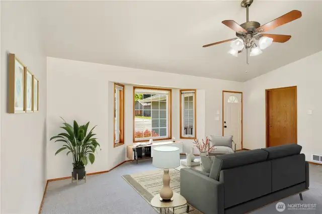 Inviting Living Room with Bay Window & Ceiling Fan – Door to the Right Leads to Laundry Room & Garage for Added Convenience!  Photo is virtually staged.