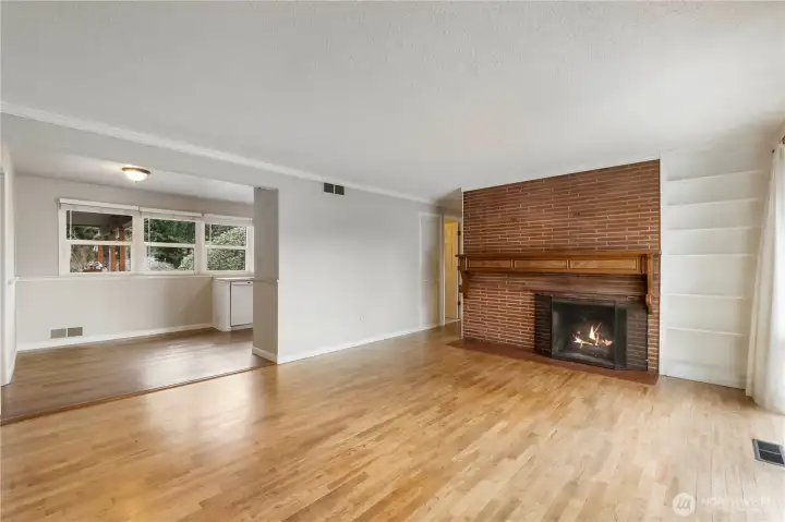 Coming in through the front door to Living Room, wood fireplace w/large mantel, hardwood floors leading into dining room and kitchen around that corner