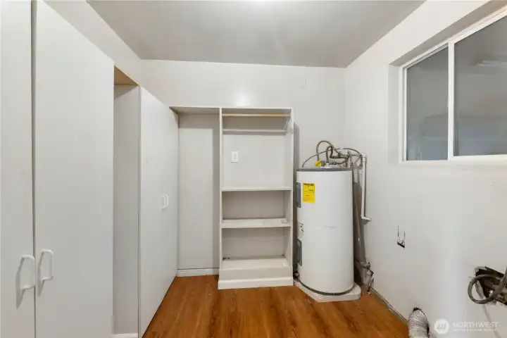 Utility room with dual pantry closets on the left, shelving, H/W tank & washer dryer hookups on the right