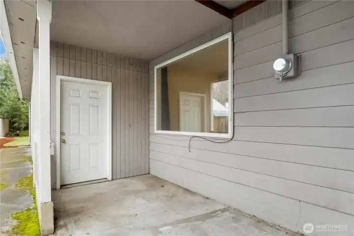 2nd Patio area with door from shop on the left and large window from family room on the right. Concrete walkway to back yard on the far left & it continues the other direction to the front yard too