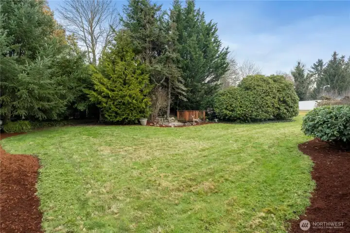 Large back yard at end of concrete walkway along west side of home.