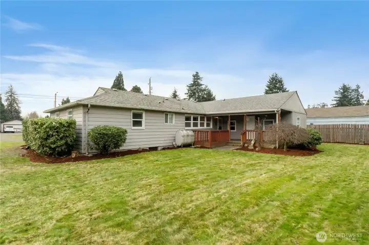 Back view of the house and covered patio. Beautiful lawn and mature landscaping