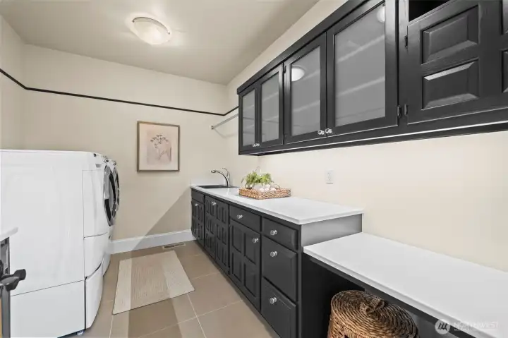 Utility meets high-end aesthetics. Striking black cabinetry with elegant fogged-glass inserts elevates the laundry room into a sophisticated workspace that mirrors the home’s overall modern design.