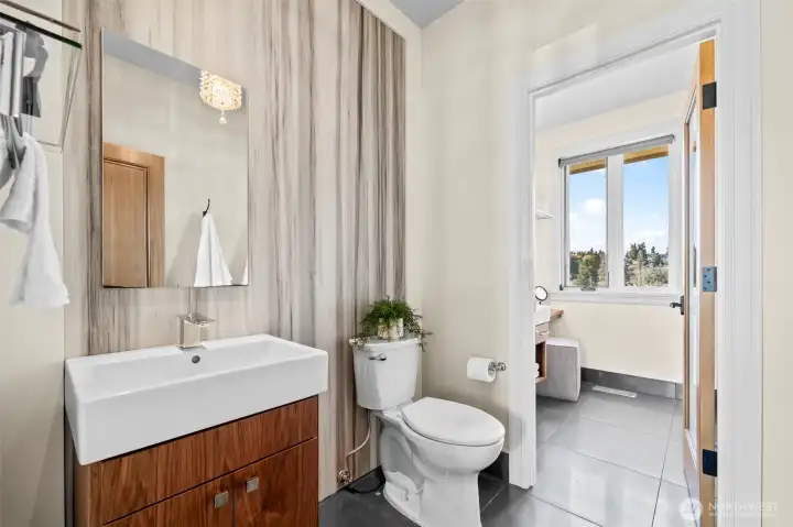 This shared suite echoes the primary en-suite’s grandeur, utilizing a dramatic marble slab to bring texture and light-reflecting elegance to the vanity area.