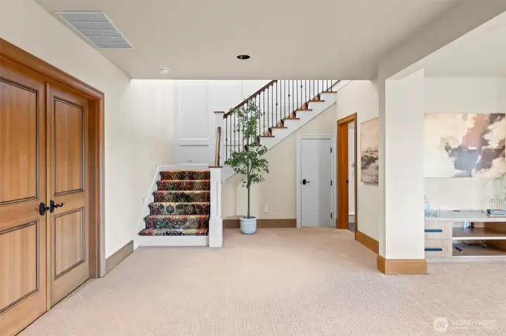 A masterful use of color and texture. The custom-designed red carpeting on the staircase serves as a bold sculptural element, creating a sophisticated focal point that leads you into the expansive lower-level retreat.