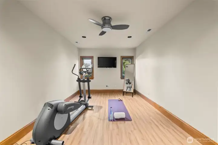 This focused gym space combines a contemporary overhead fan for a constant cool breeze with integrated media, transforming your daily routine into a premier wellness experience.