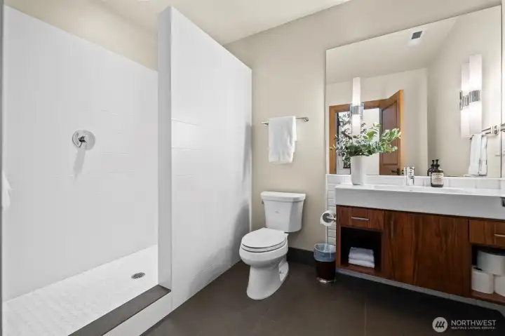 Located on the basement floor, this bathroom suite ties the bottom floor to the main designs of the home. The partially enclosed shower design provides a streamlined aesthetic, allowing the custom tile patterns to take center stage in this well-appointed lower-level suite