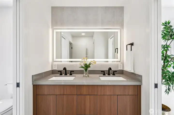 The remodeled Jack-and-Jill bathroom includes a double vanity and illuminated mirror.