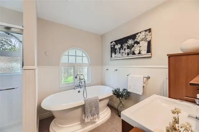 The beautifully updated large bathroom has a soaking tub with a arched window above to bring in the light. Wainscoting walls and newer paint. Newer flooring. Updated plumbing.
