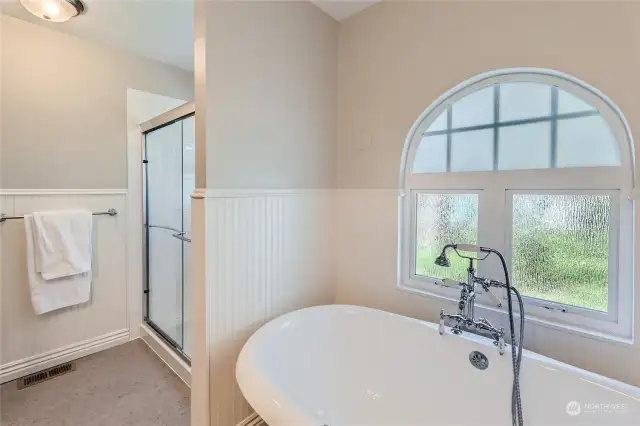This bright spa-like bathroom has a privacy window in the shower and over the soaking tub.  New shower head.  Unique newer vintage style bathtub fixture.  Newer flooring. Newer paint.