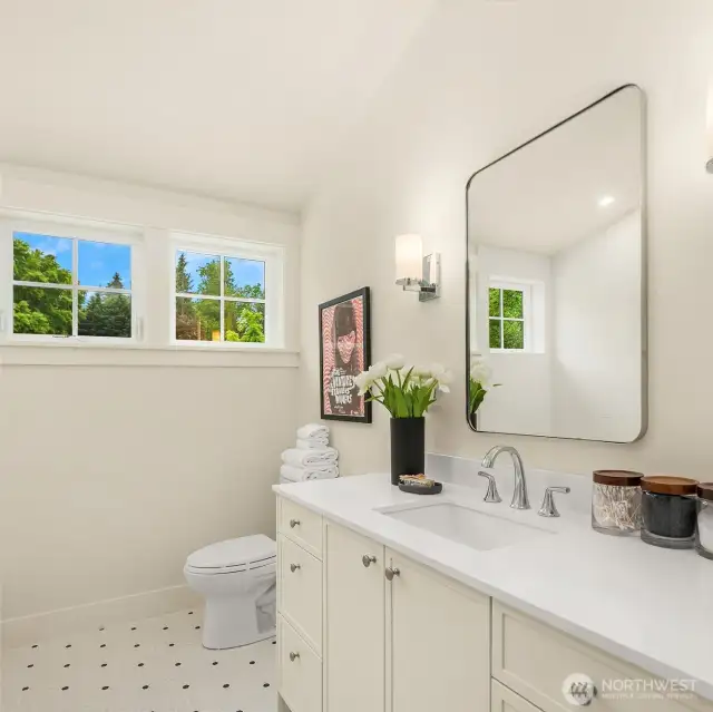 The 3rd level full bath includes custom tile, gleaming quartz counters, a large vanity, a laundry, and dormers that fill the space with light