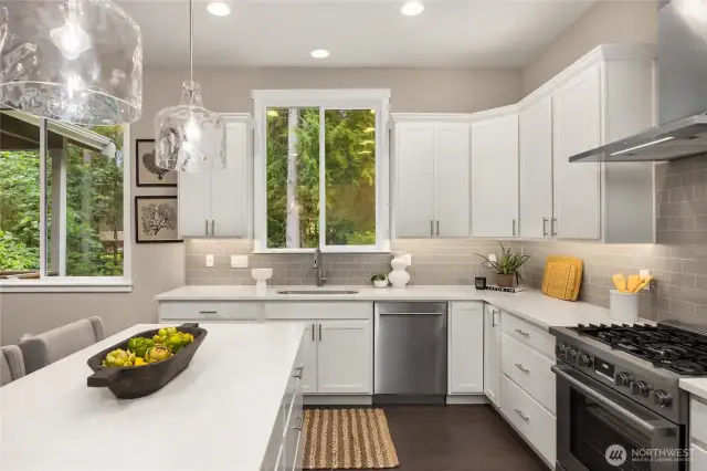The window over the sink looks out to woodlands and the Ferry Dell Trail. Appliances include the Wolf range with propane cooktop and Bosch dishwasher.