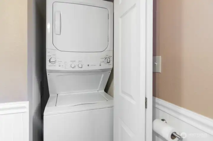 Stackable washer and dryer are in a closet in bathroom, offering convenience and space saving.