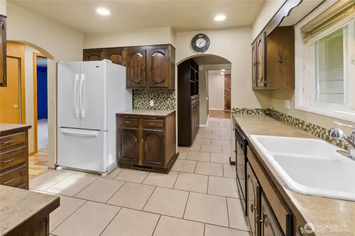 Centrally located between gathering spaces, the kitchen boasts tile flooring and a functional layout.
